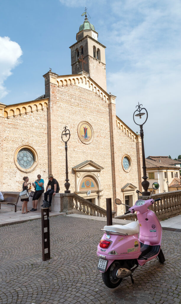 Ansicht der Kirche in Asolo. Im Vordergrund ist eine pinkfarbene Vespa zu sehen.