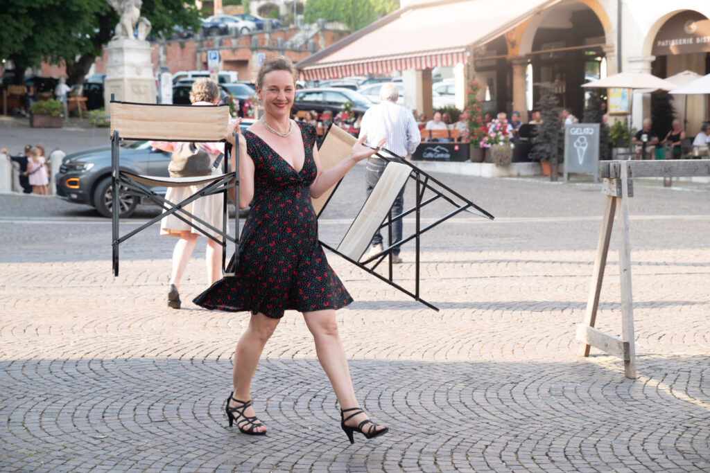 Die Sängerin trägt zwei Stühle auf der Piazza Garibaldi in Asolo